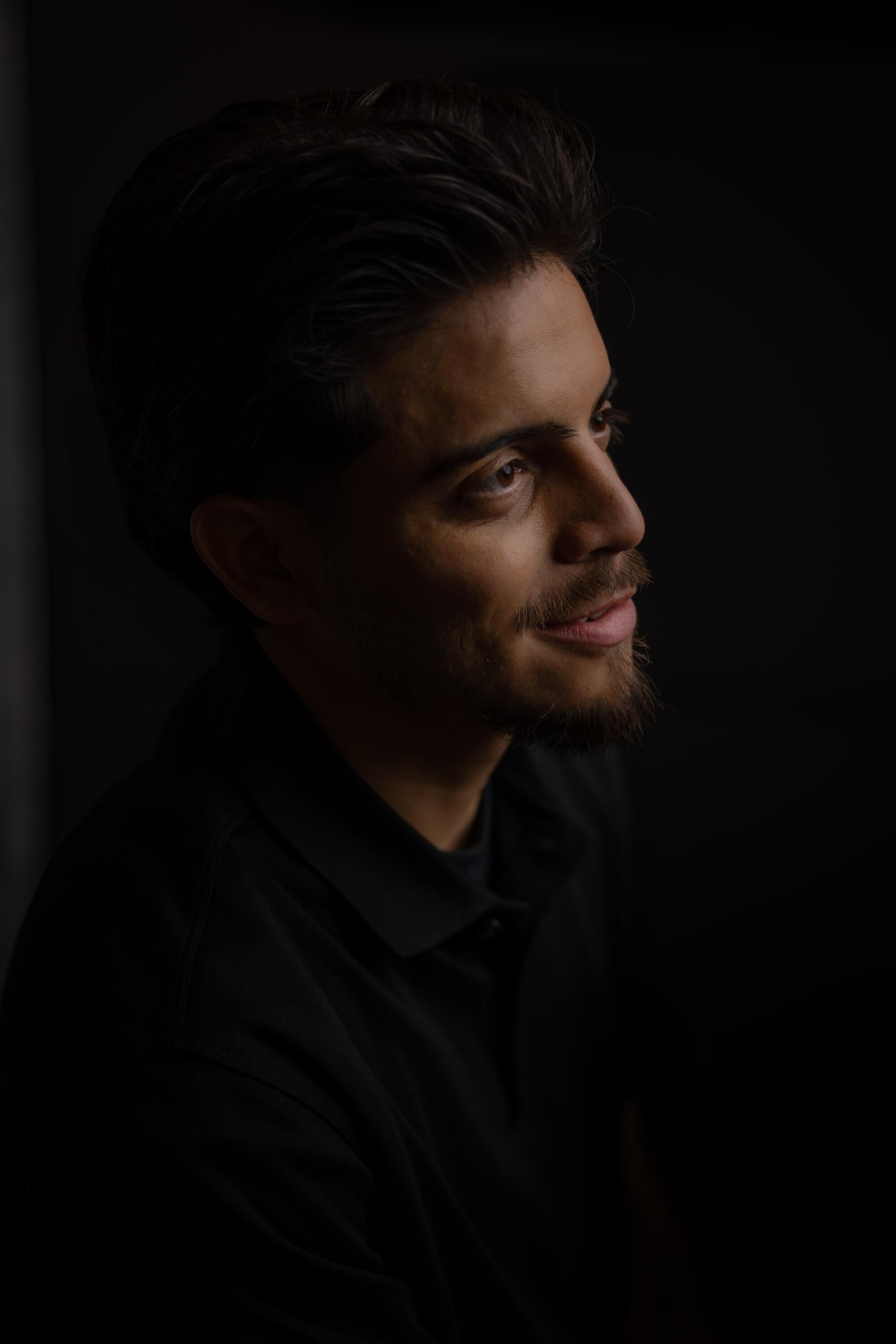 Profile view of a man in a shadowy background.
