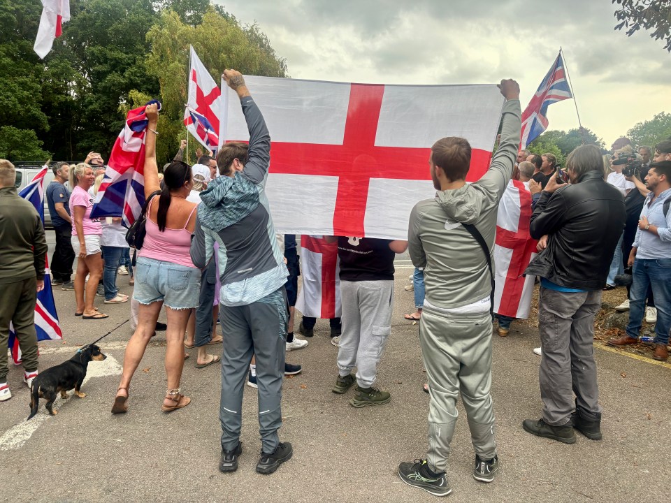 Protestors holding English flags outside a hotel.