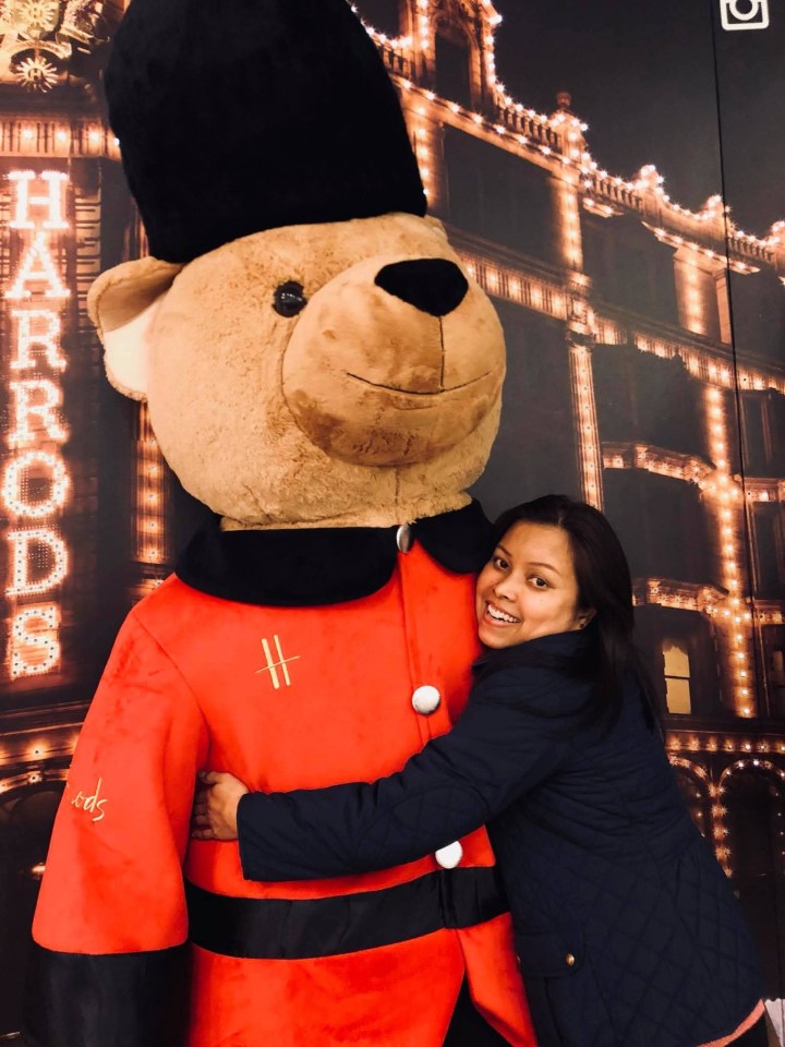 Woman hugging large teddy bear in Harrods uniform.