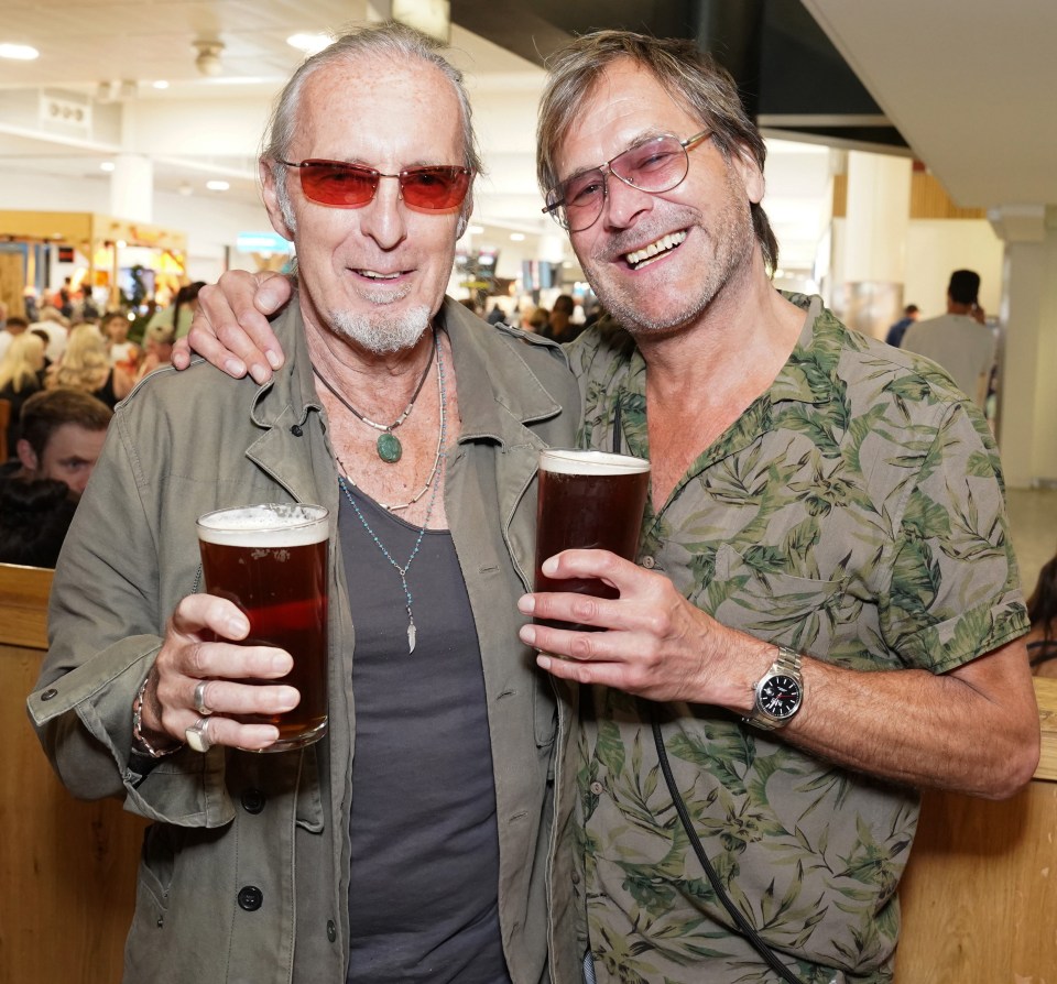 Steve Norman of Spandau Ballet and a friend holding pints of beer.