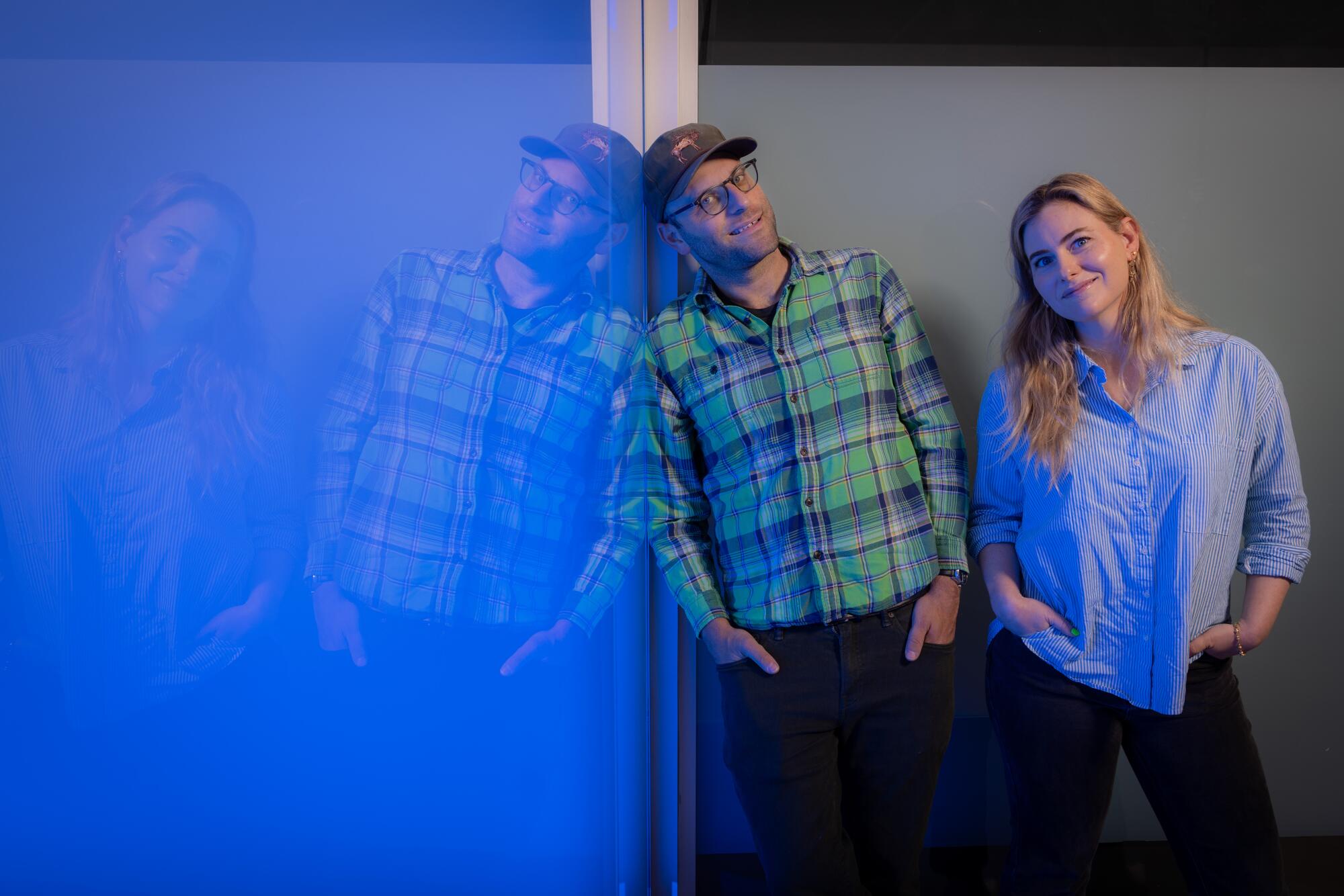 two people leaning against a blue wall