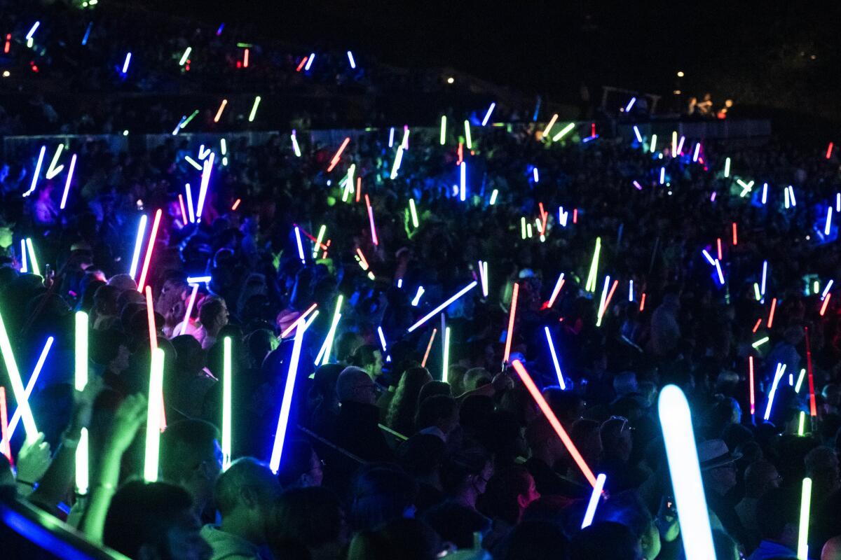 Fans at the Hollywood Bowl waving various colored light sabers.