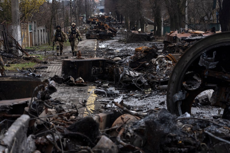 Soldiers walk past destroyed Russian tanks in Bucha, Ukraine.