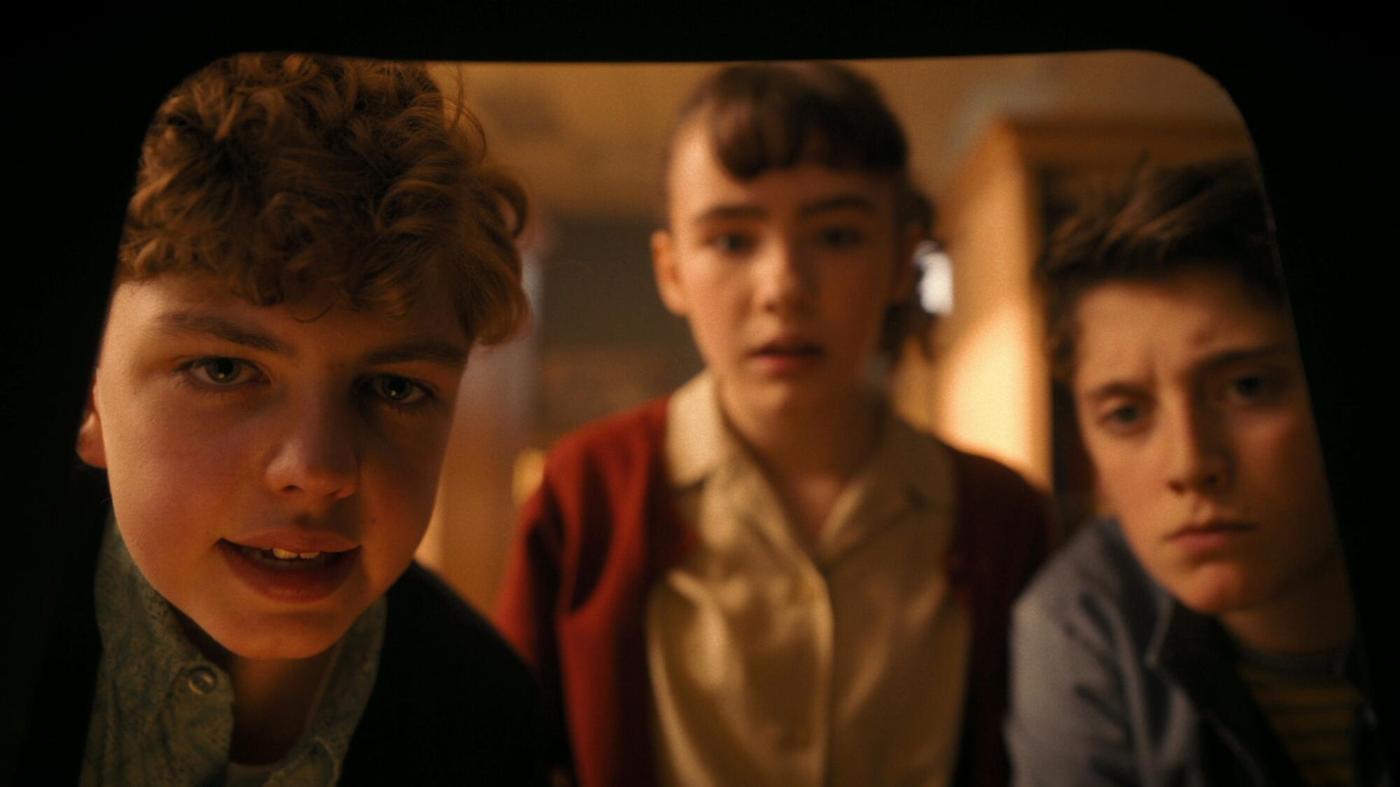 Three children looking intently at something out of view.