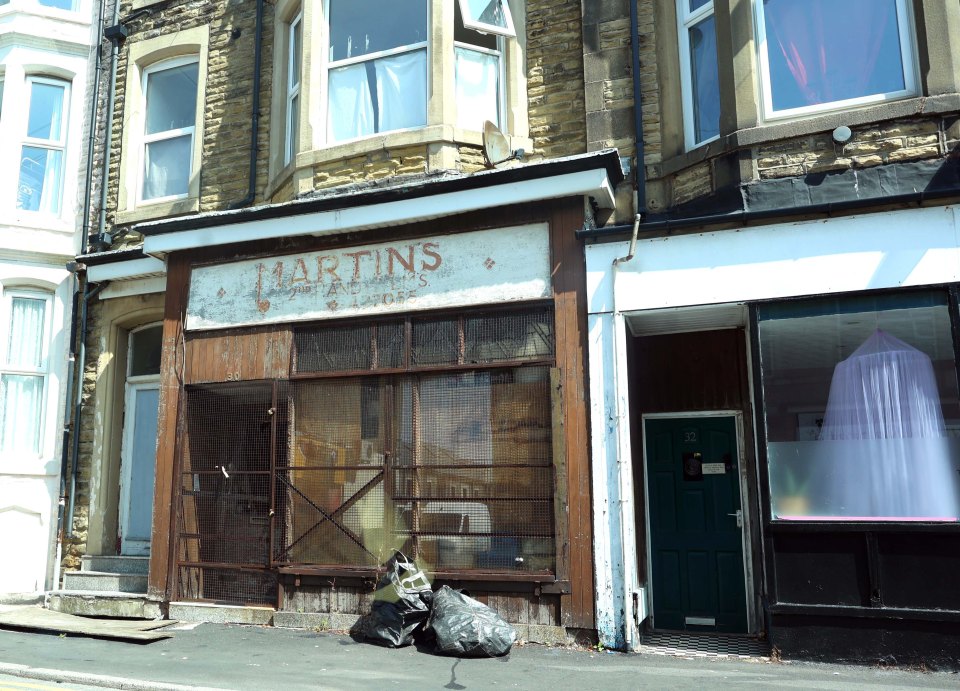 A boarded-up shop with faded signage that reads "Martins 2nd Hand Lvs 192055".