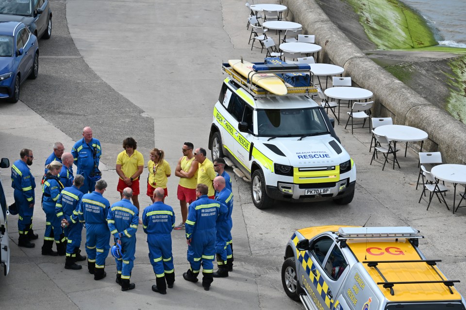 Emergency responders gathered near rescue vehicles after a woman was recovered from the sea.