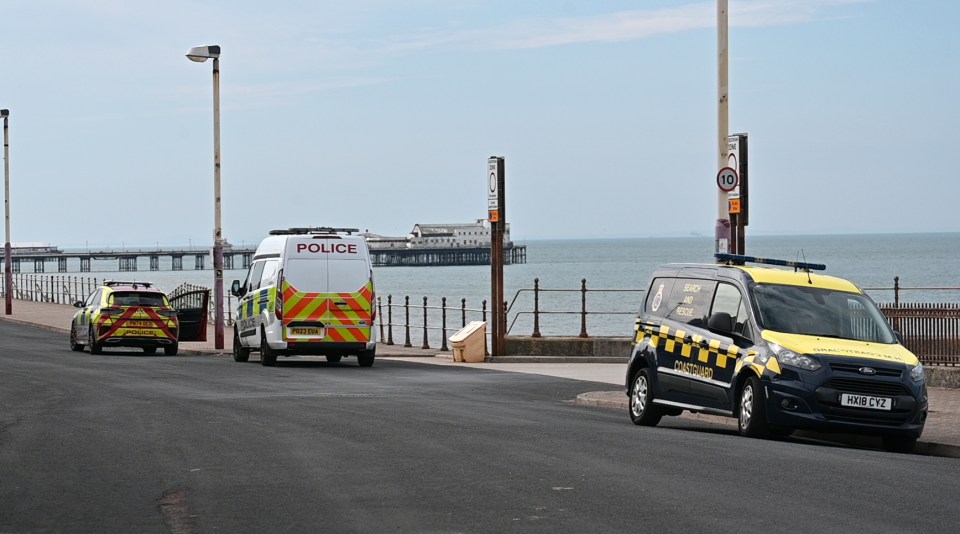 Police and coastguard vehicles at a seaside incident.