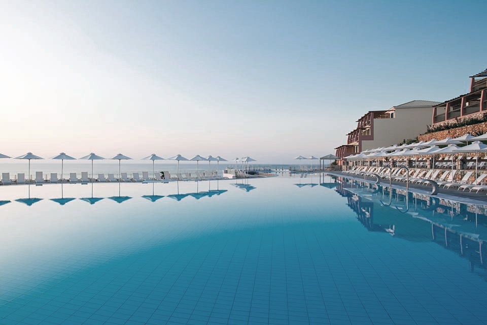 Oceanfront resort pool with lounge chairs and umbrellas.