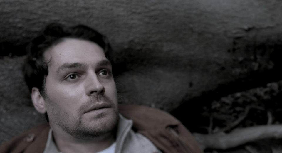 A man lying on the ground, appearing injured.