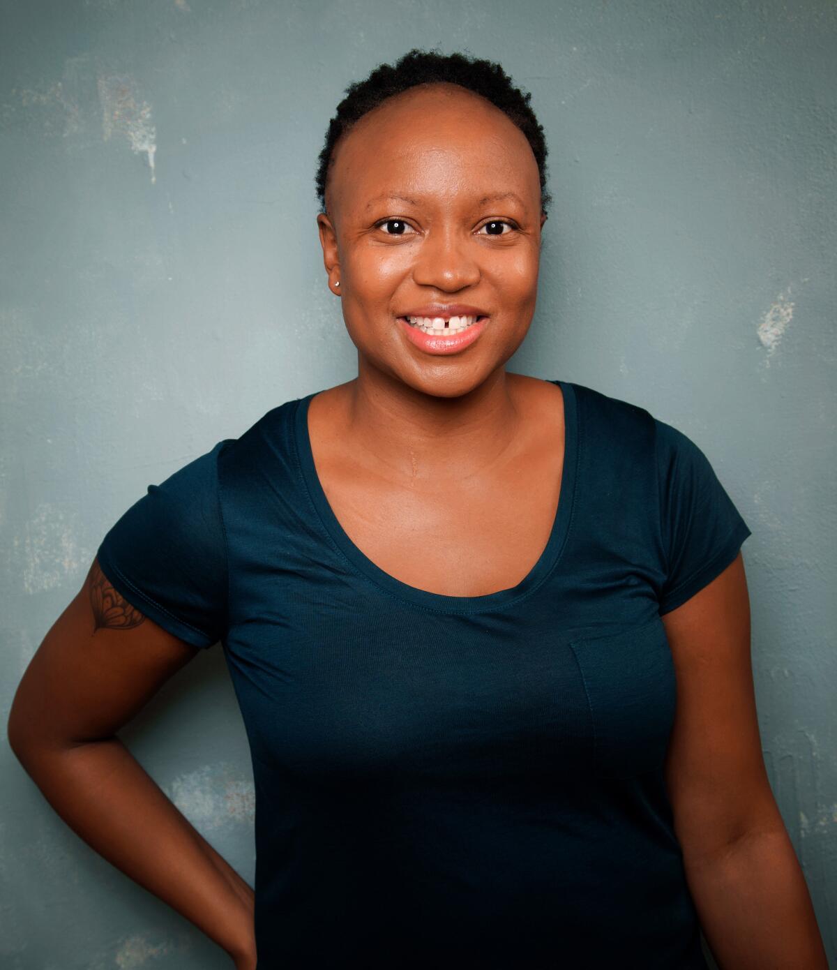 Kashana Cauley, wearing a teal T-shirt, smiles at the camera.