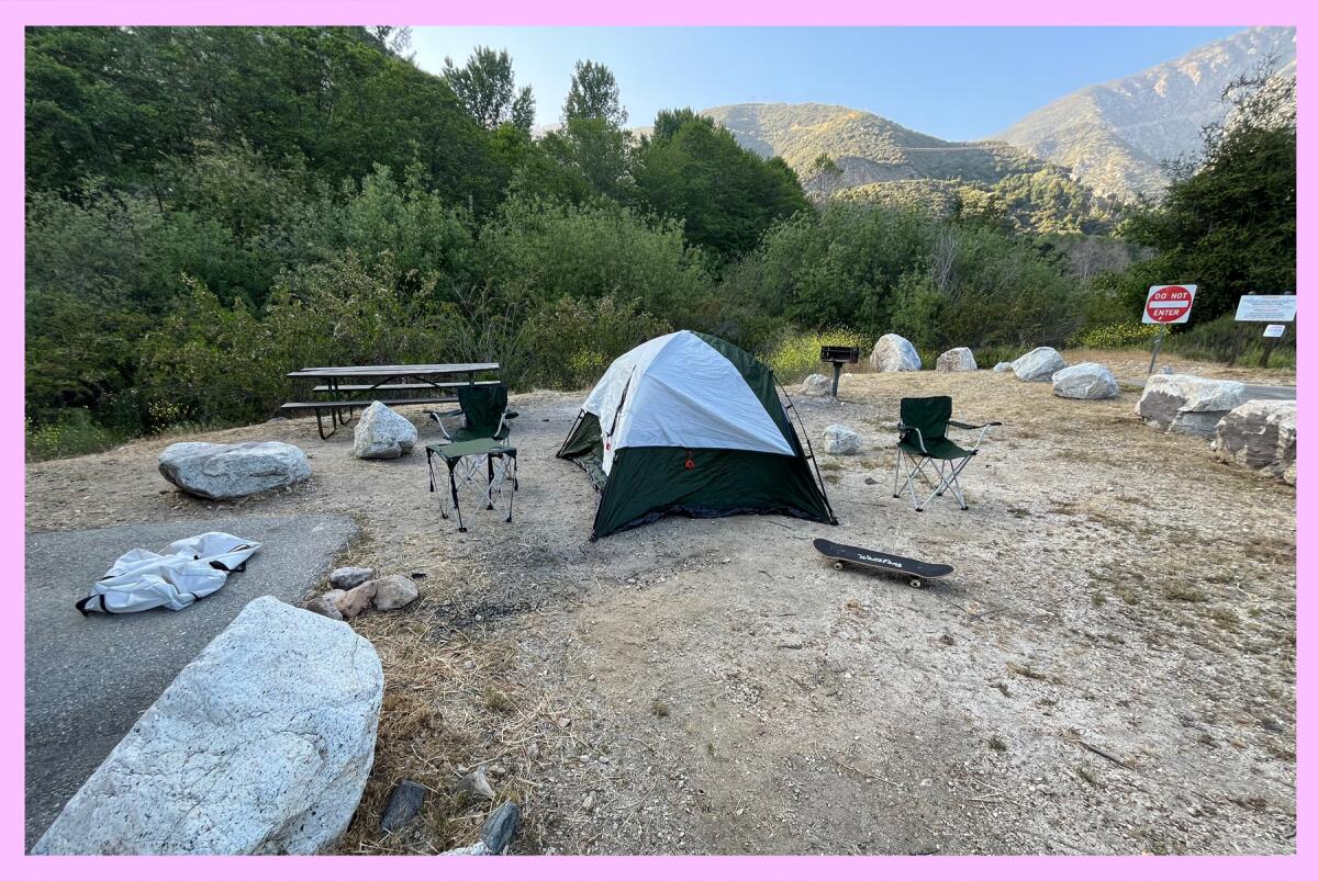 A tent and campsite with mountains in the background.