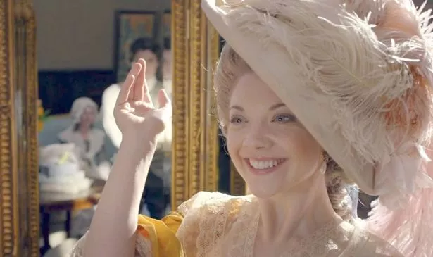A woman in a pink hat and a yellow dress smiles