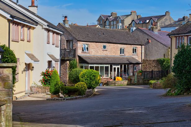 A residential street features houses of varying heights and colors under a bright sky in Heysham - Lancaster district - Lancashire - Great Britain