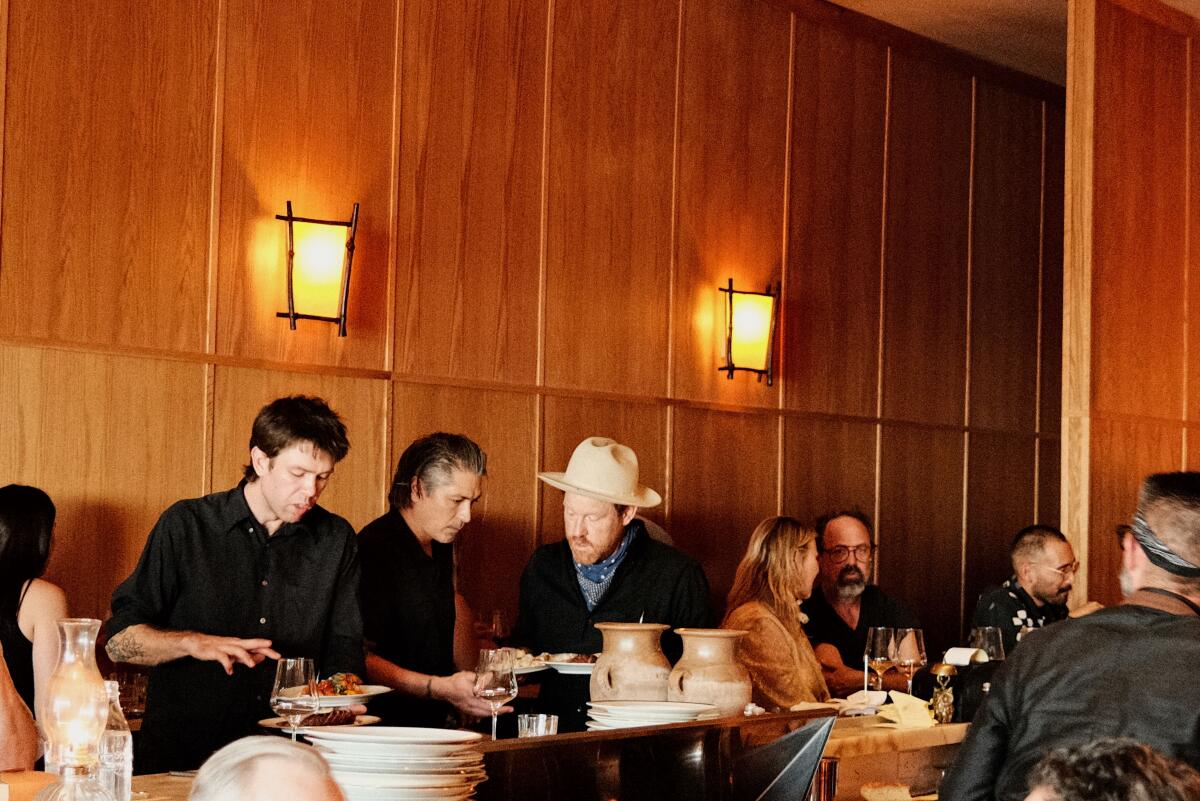 Three men huddle at the bar overlooking the hearth at Betsy in Altadena.