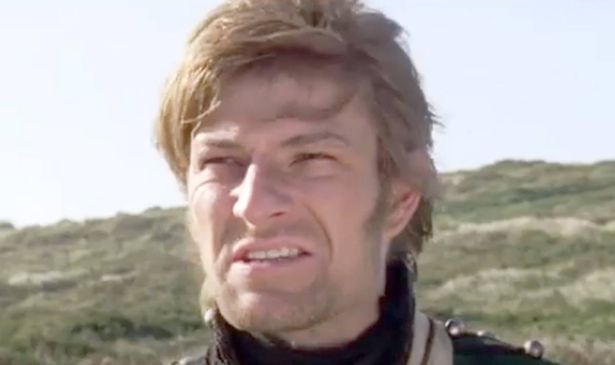 A man grimaces as he stands outside