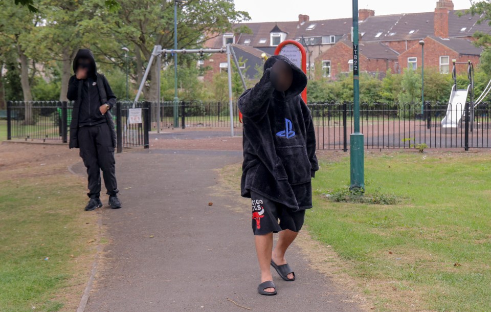 Two hooded figures in a playground.