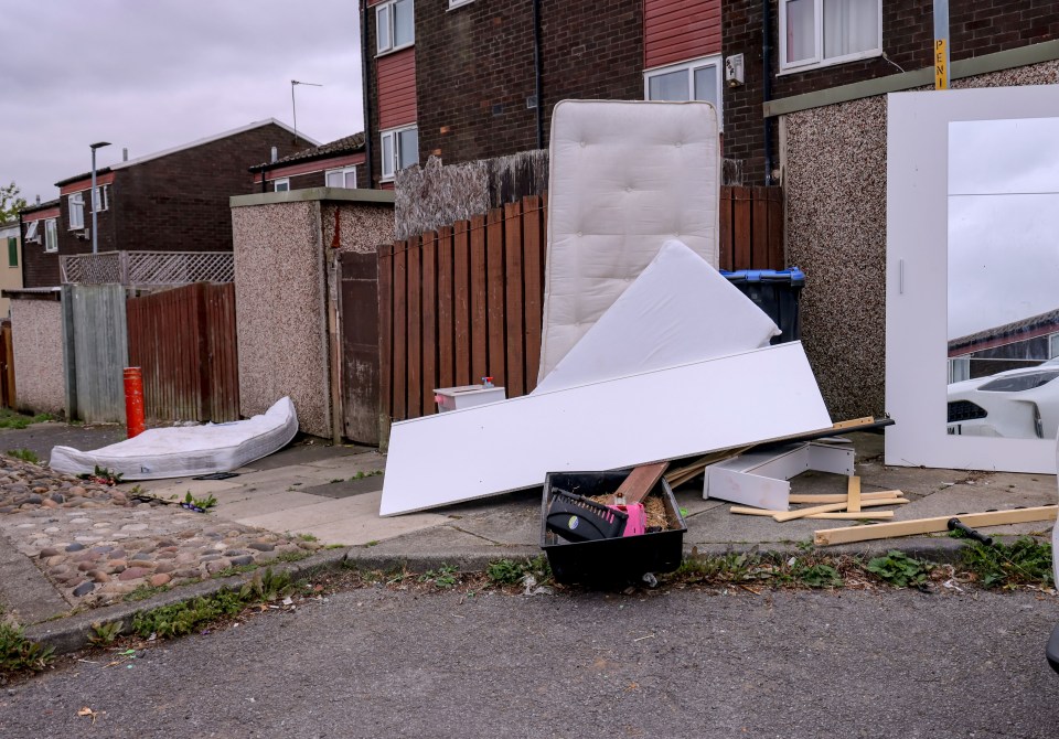 Fly-tipped mattresses and furniture on a residential street.