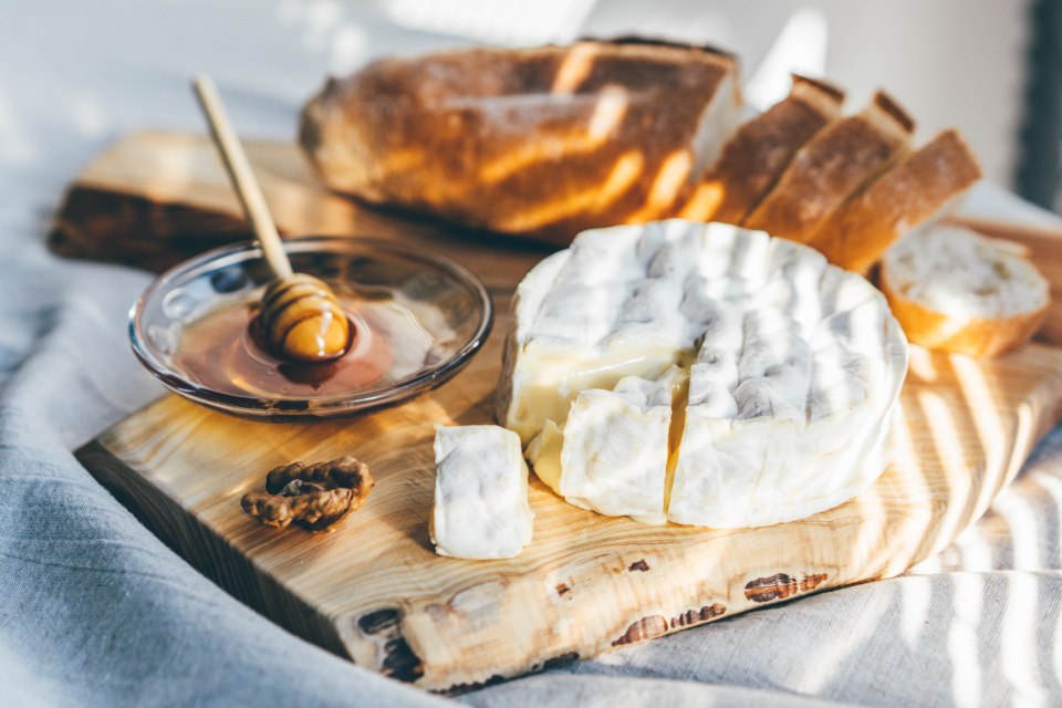 Cheese board with camembert, honey, baguette, and walnut.