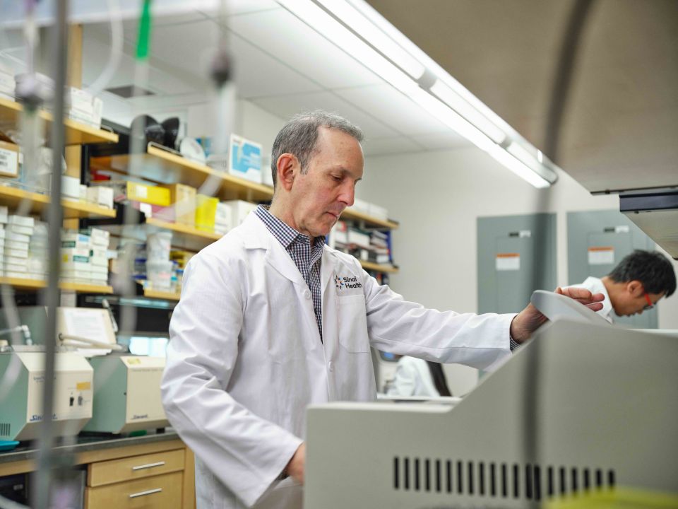 Scientist in lab coat operating lab equipment.
