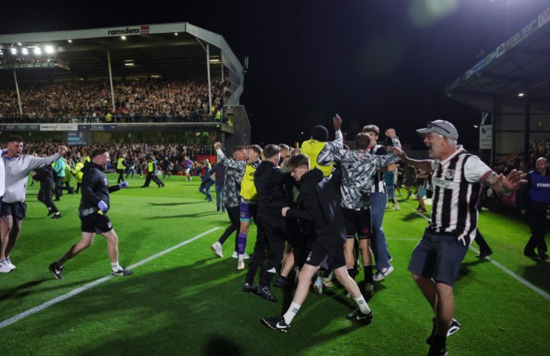Grimsby Town fans celebrate on the pitch after the match against Man Utd