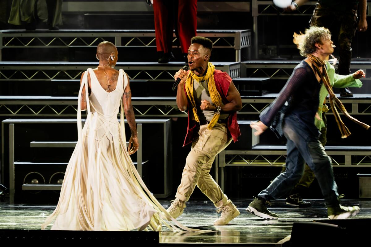 Tyrone Huntleys sings passionately into a microphone on stage as Simon in "Jesus Christ Superstar."