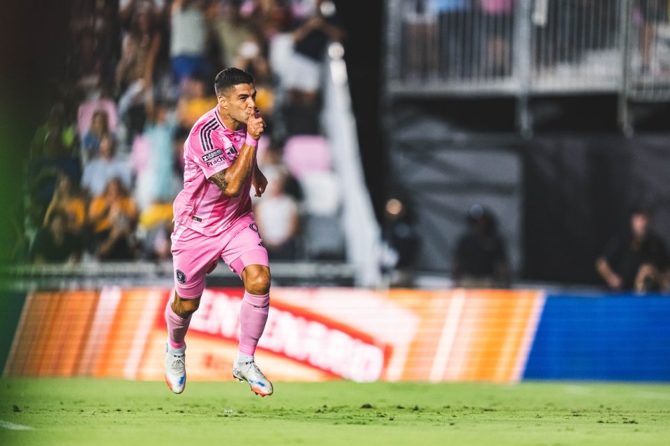 Soccer player in pink uniform celebrating a goal.
