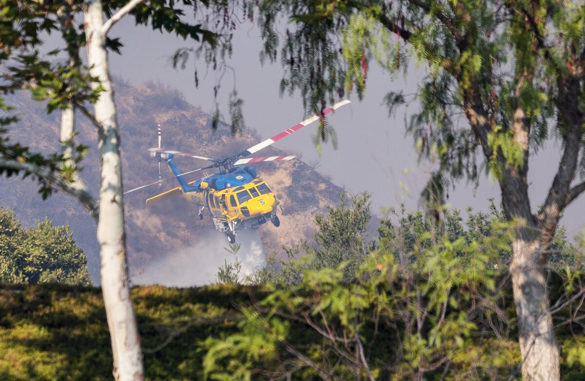A Ventura County Fire Department helicopter makes a water drop on the hillside at Hasley Estates in Castaic on Friday.