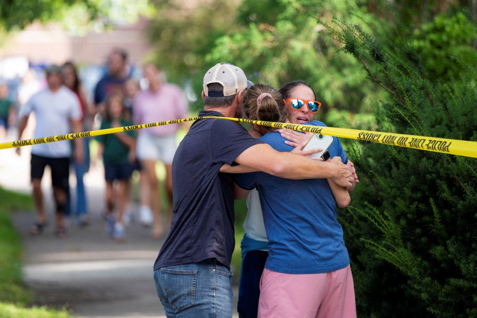 People hugging behind police tape.
