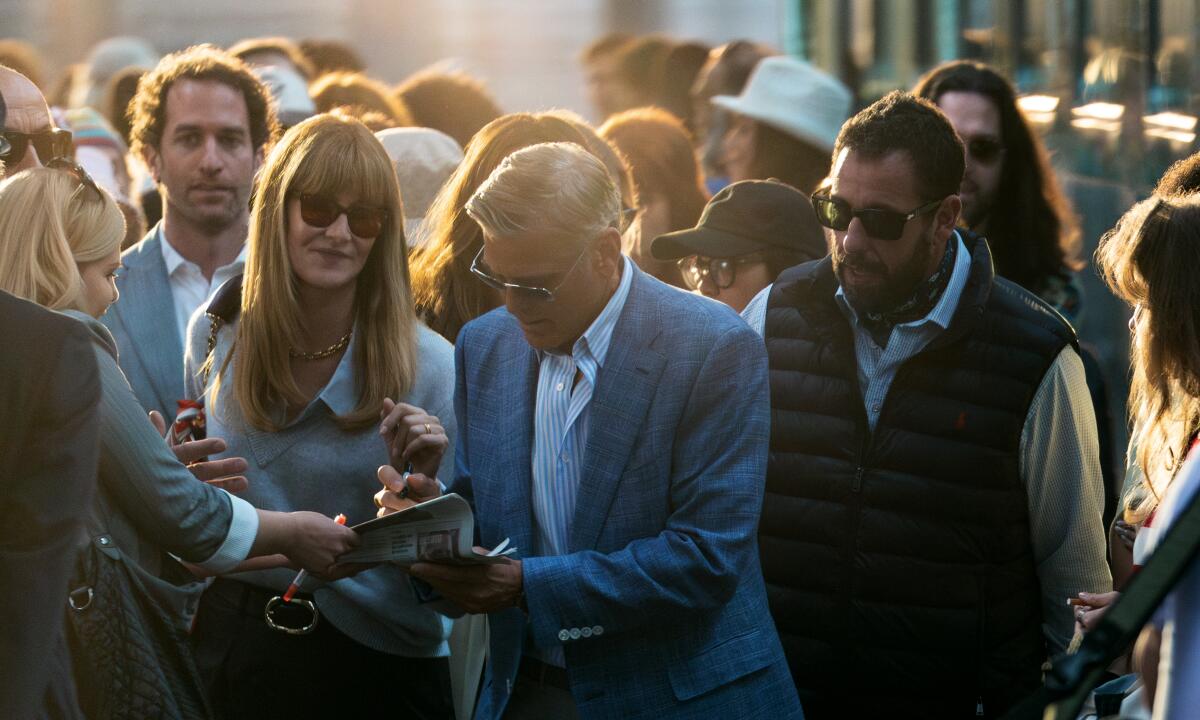 A celebrity signs autographs in a crowd.