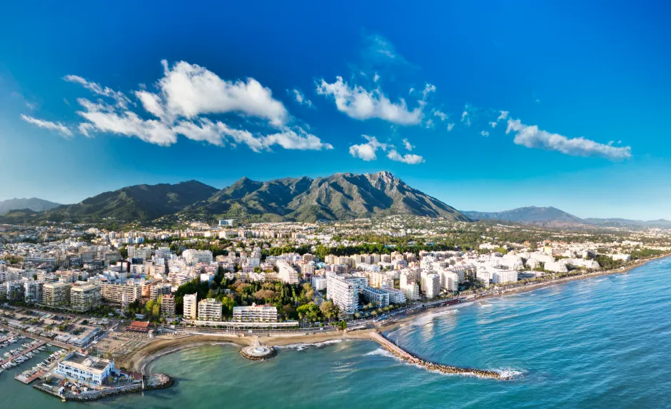 Aerial view of a coastal city with mountains in the background.