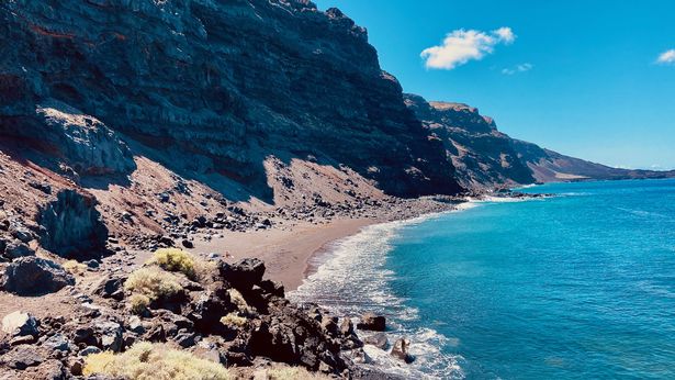 A view of the beach and rocky cliffs making up the island landscape of El Hierro