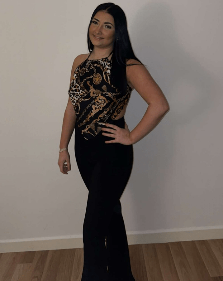 Woman in black pants and patterned halter top.