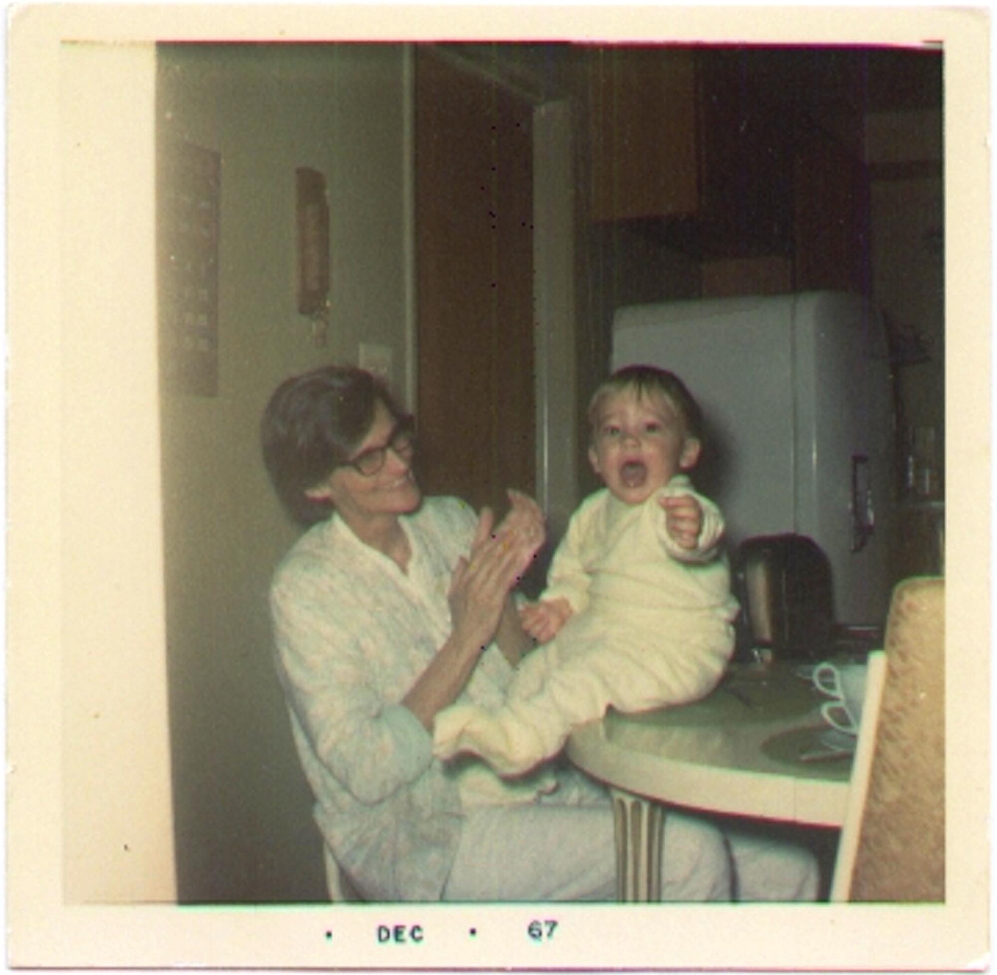 A seated woman with a baby on a table.