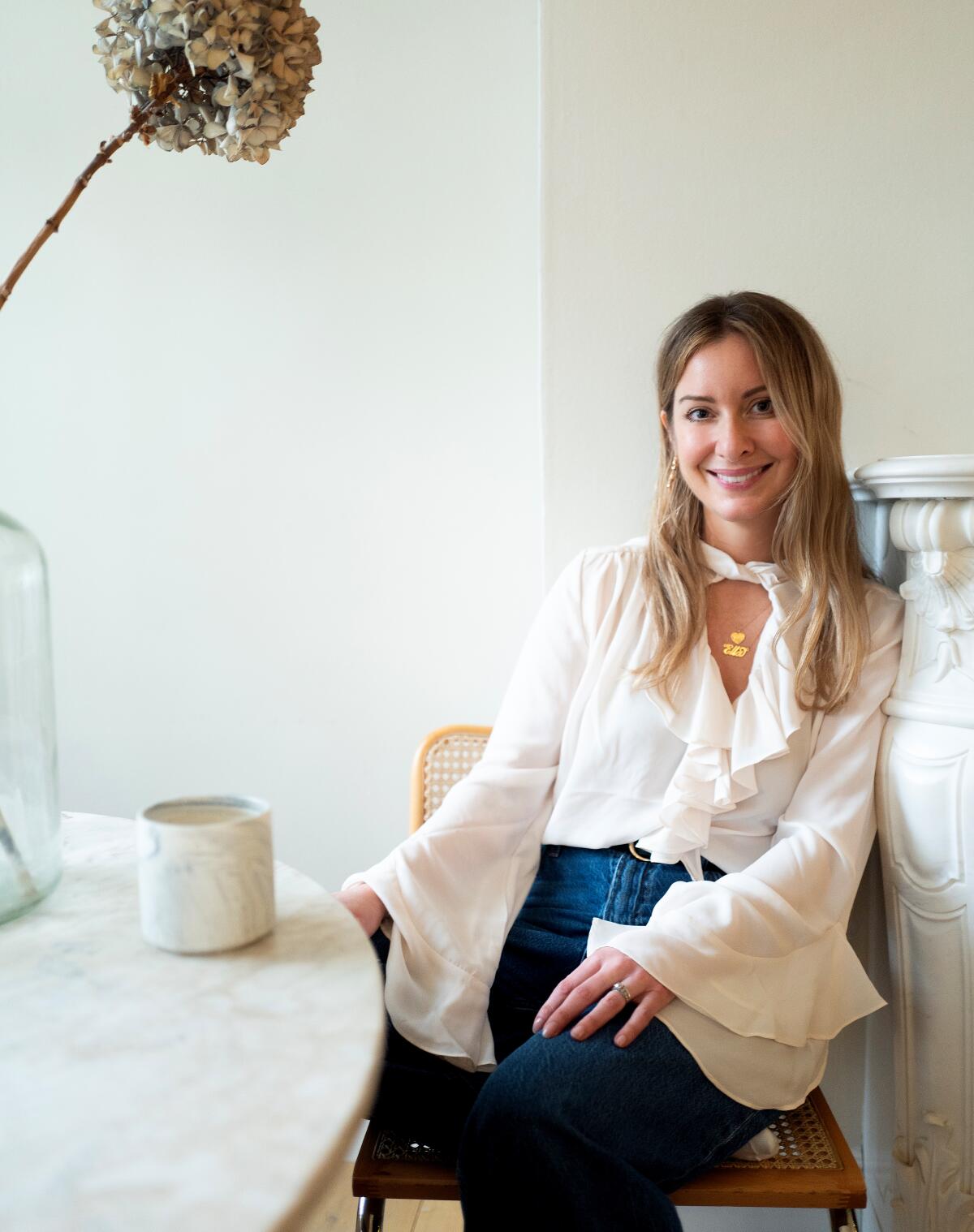 Ella Berman leans against a marble fireplace as she sits at a marble table.