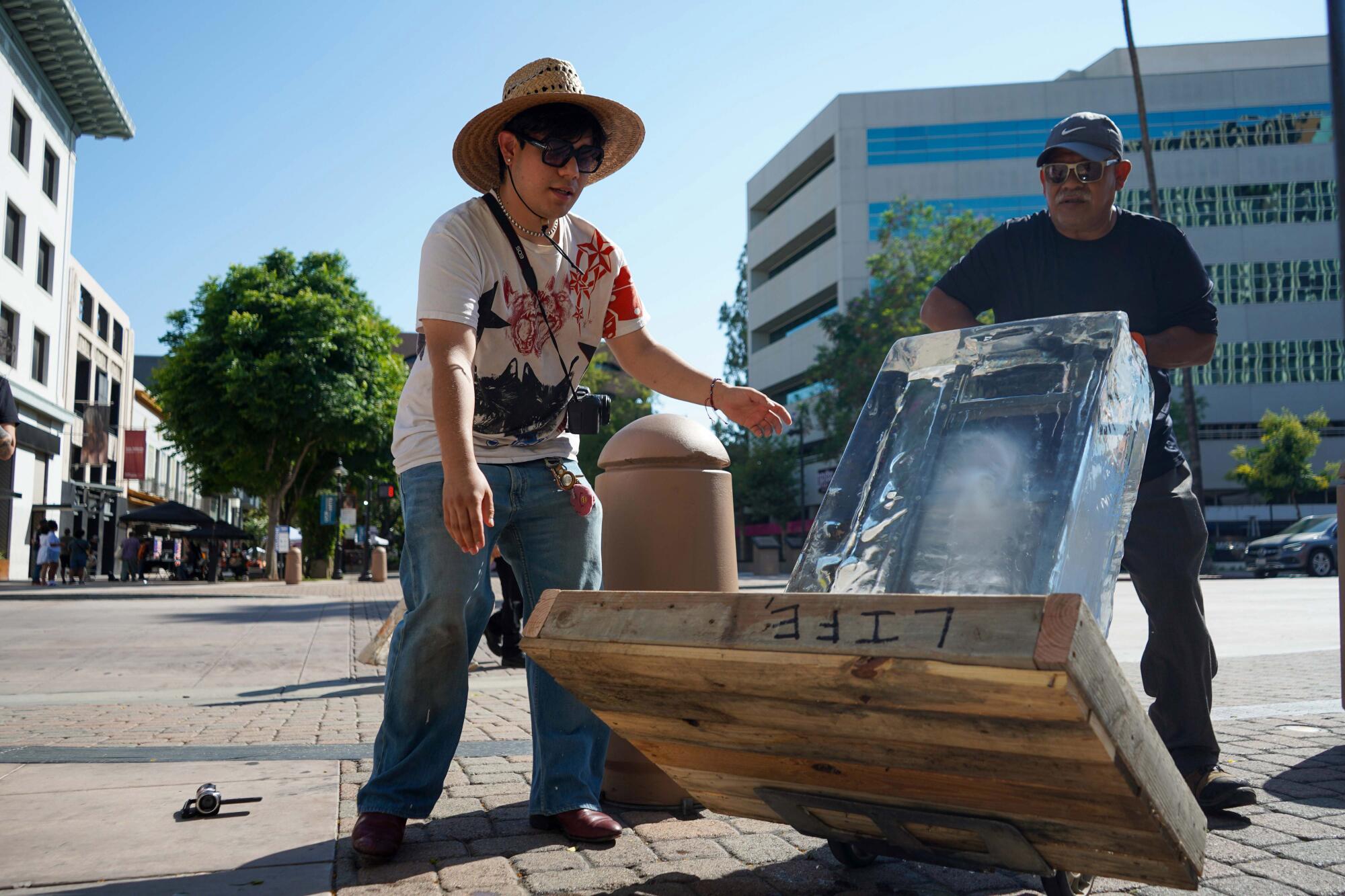 Perry Picasshoe and his father place the ice block near the city's monthly arts walk in downtown Riverside on July 3, 2025.