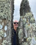 A man in sunglasses stands between two mossy rocks