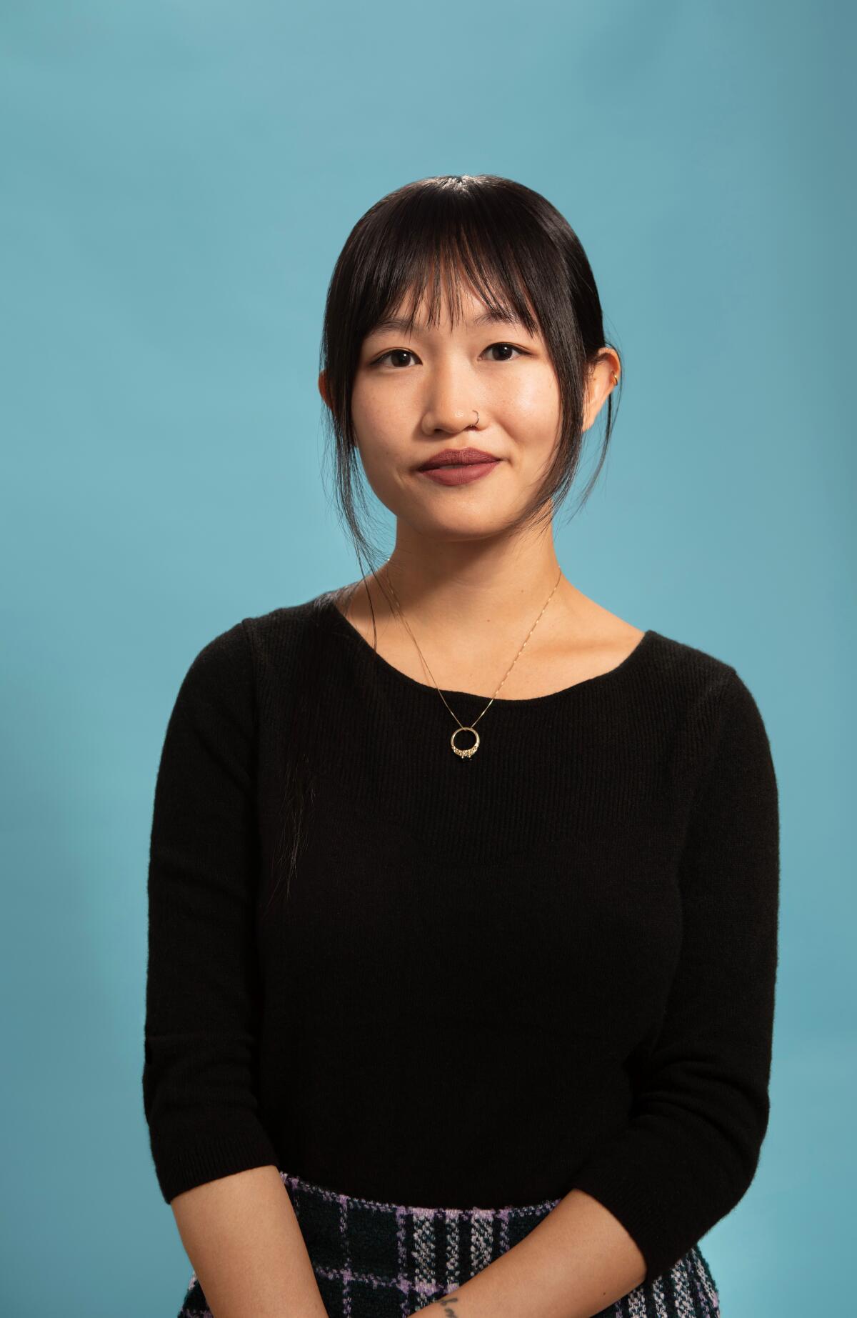 R.F. Kuang sits in front of a blue backdrop.