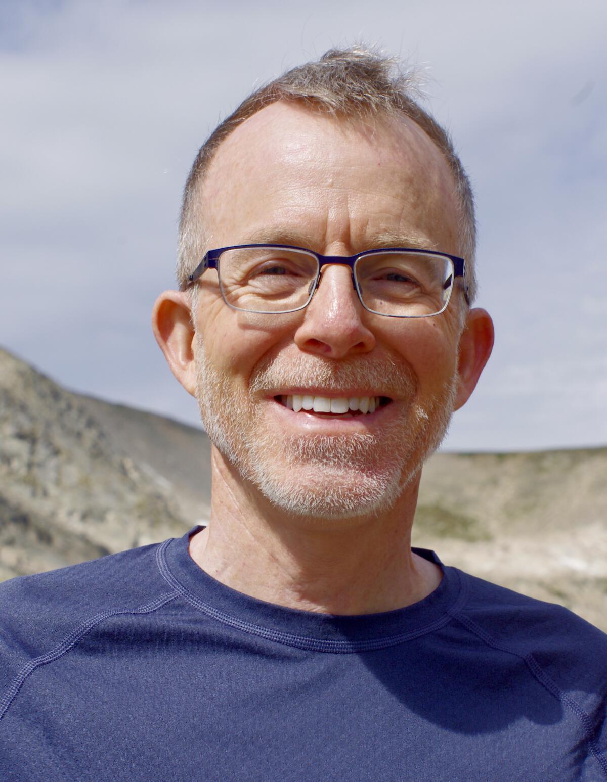 David Baron, wearing glasses, smiles into the camera.