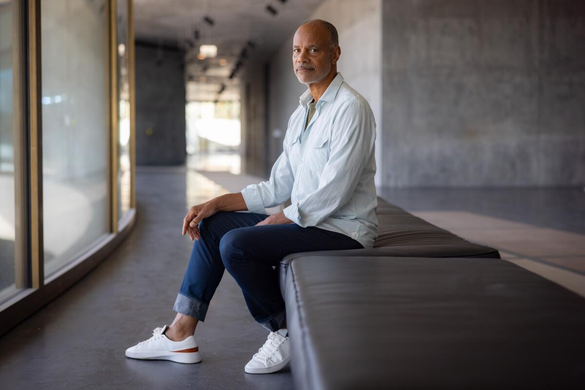 Todd Gray, in a collared shirt and jeans, poses for a portrait.