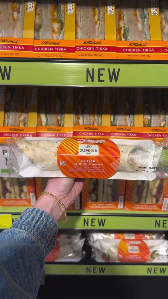 Hand holding a new M&S Butter Chicken Wrap in a store.