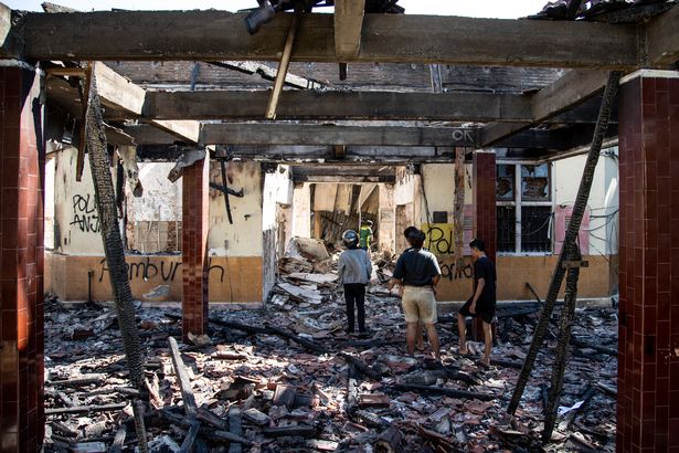 People look around in a burned Indonesian Police Office building