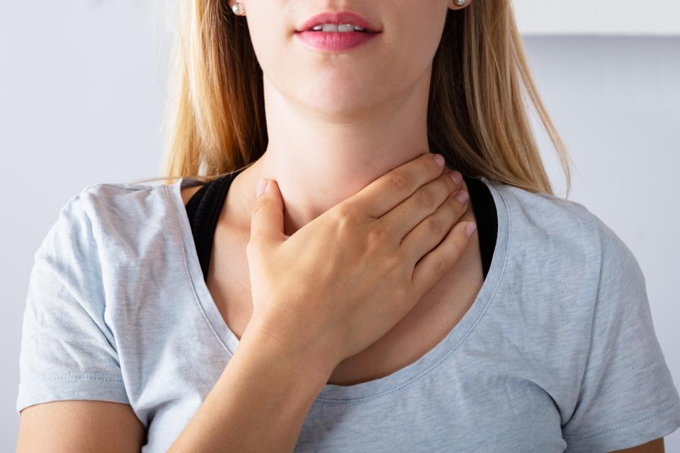 Close-up of a woman touching her throat.