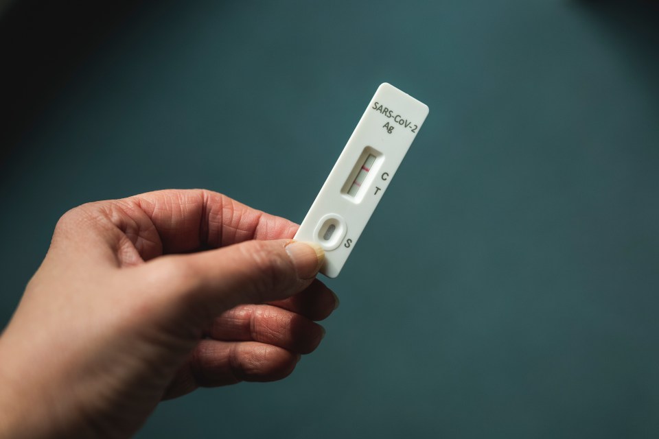 Hand holding a positive COVID-19 rapid antigen test.