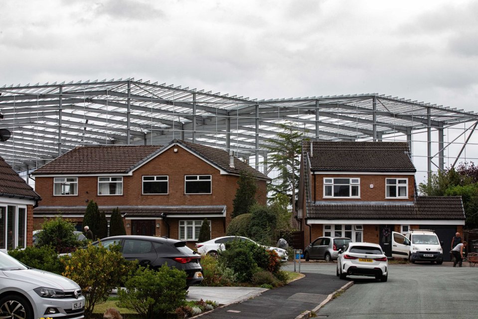 Large steel structure under construction behind residential homes.