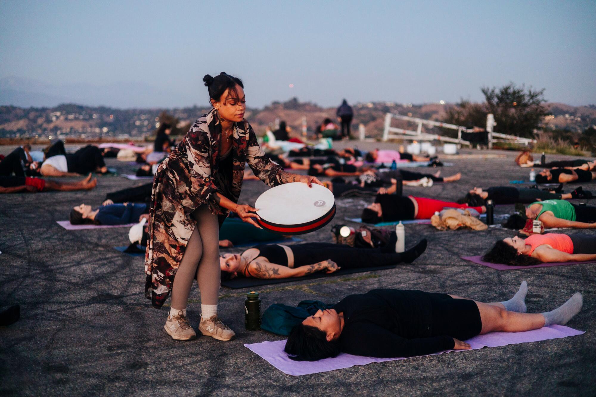A person plays instruments while others lie on yoga matts.