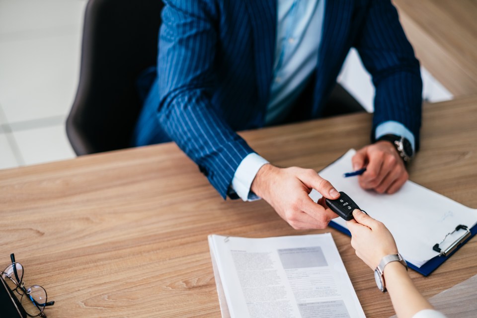 A businessman receives car keys from a salesperson.
