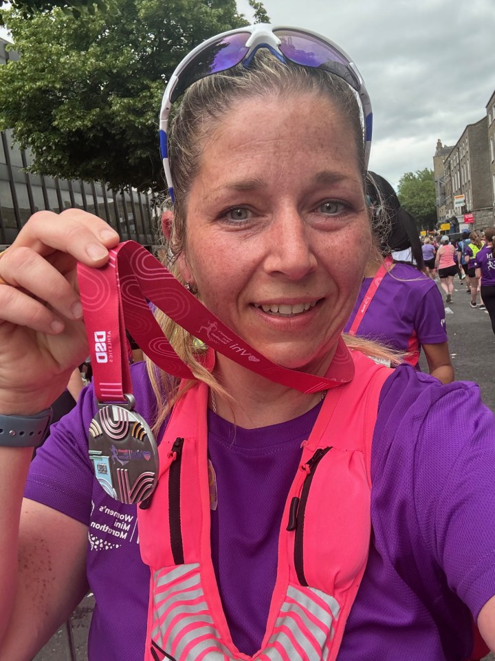 Woman holding a Women's Mini Marathon medal.