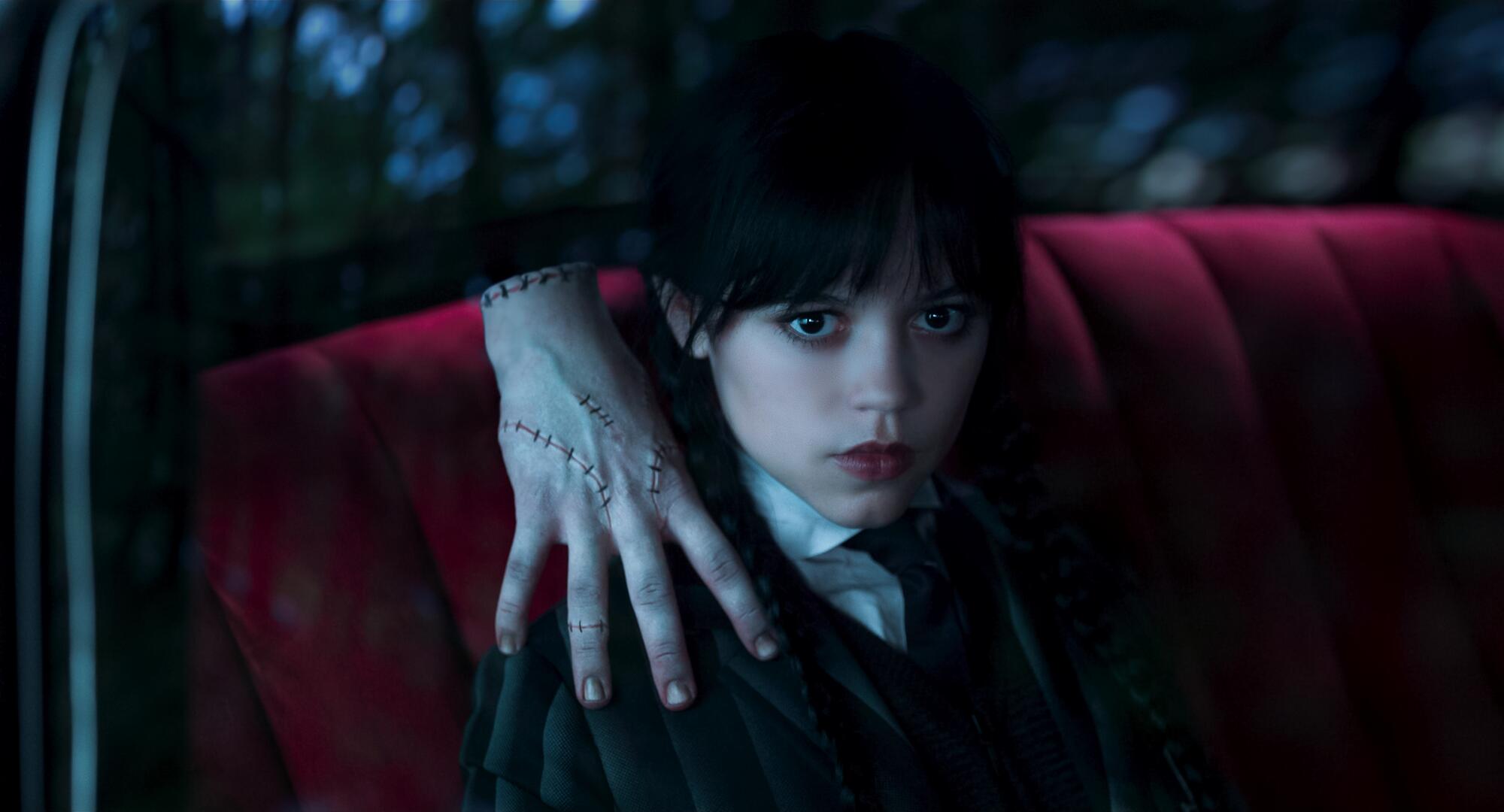 A lone hand rests on the shoulder of a young girl.