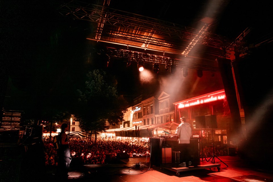 DJ performing at an outdoor concert for a large crowd.