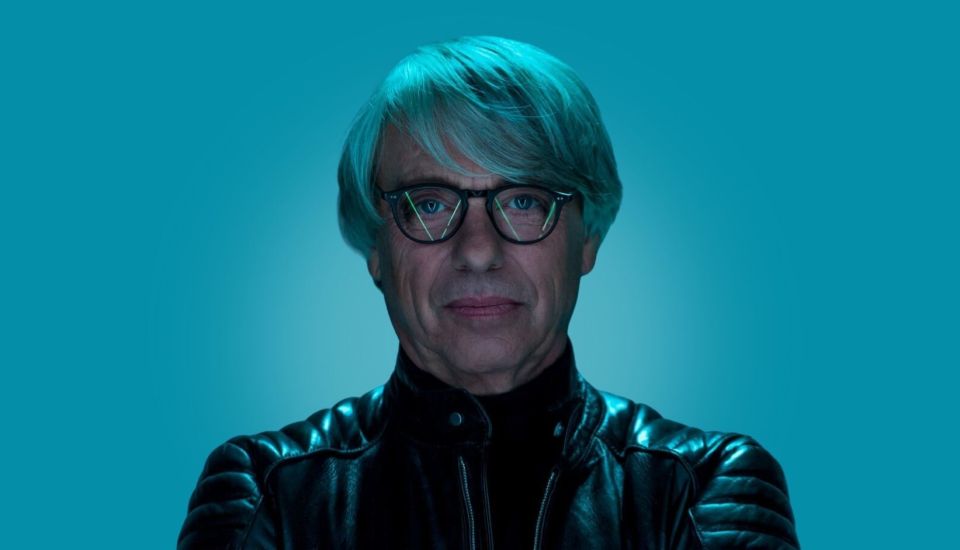 Portrait of a man with teal hair and glasses wearing a black leather jacket.